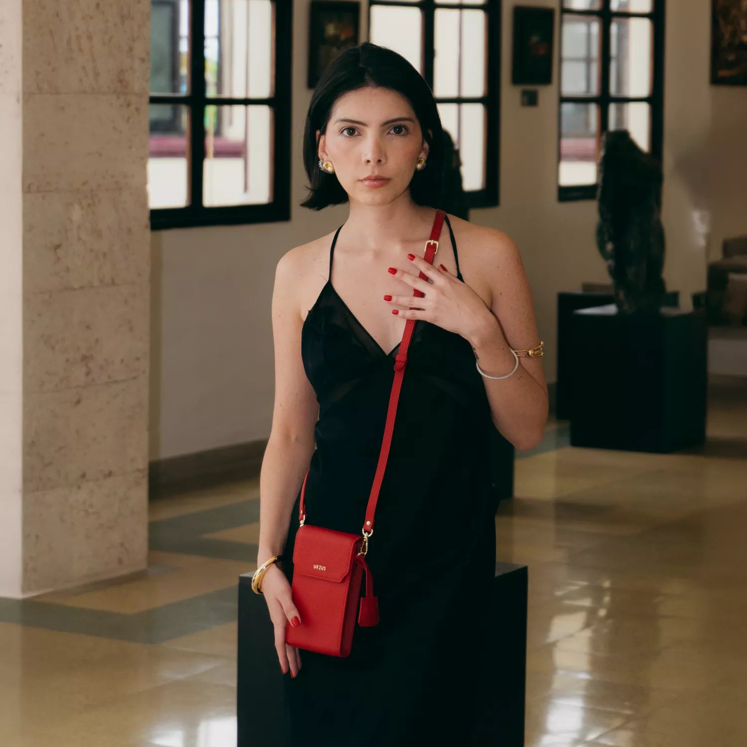 Mujer luciendo el Boreal Bolso Cruzado Compacto en cuero Rojo de Urzus, ideal para llevar billetera, tarjetero, celular y accesorios con seguridad y elegancia.